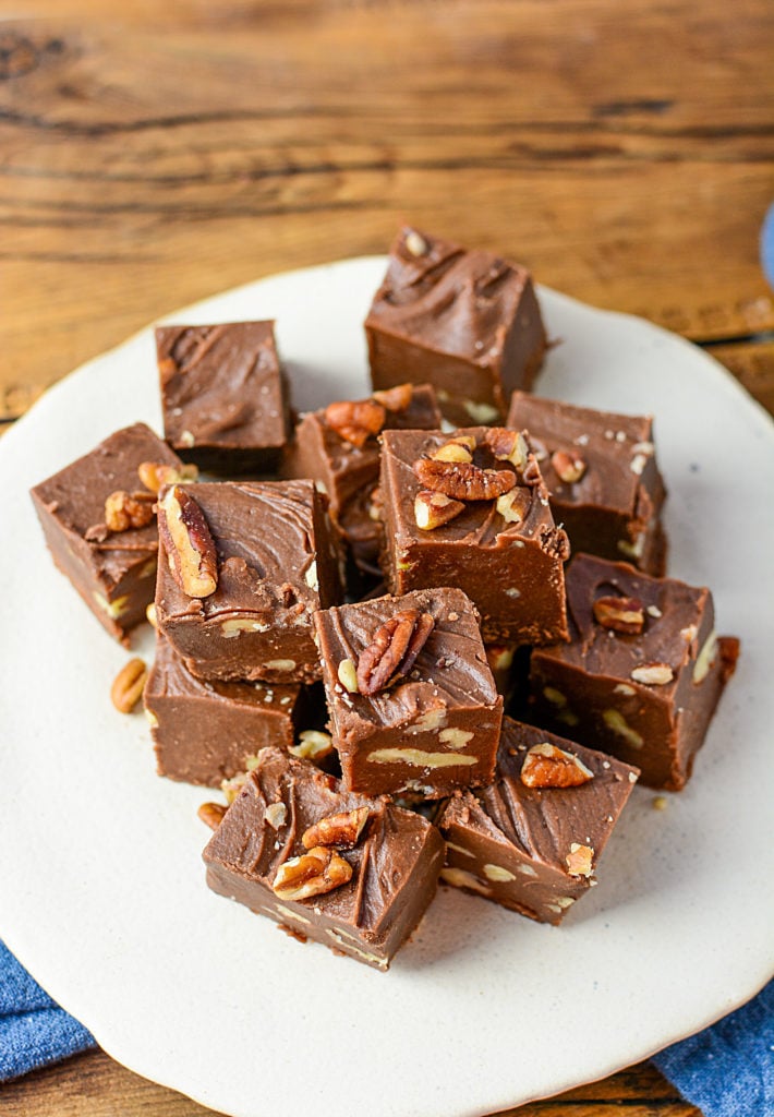 et bilde av blokker av sjokolade fudge med nøtter, sitter på en hvit plate.