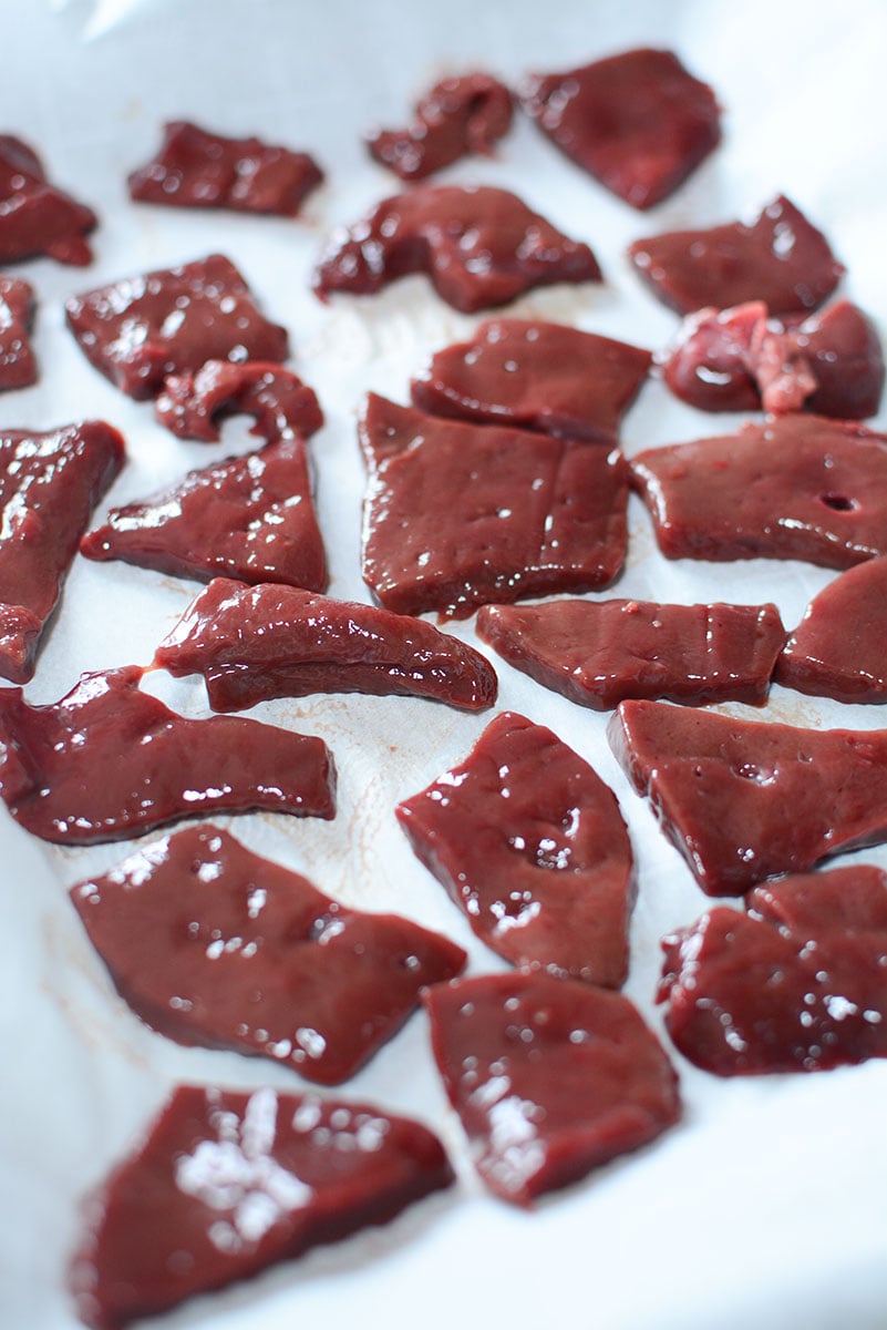 24 little pieces of fresh beef liver laid out on a baking pan, lined with a parchment sheet