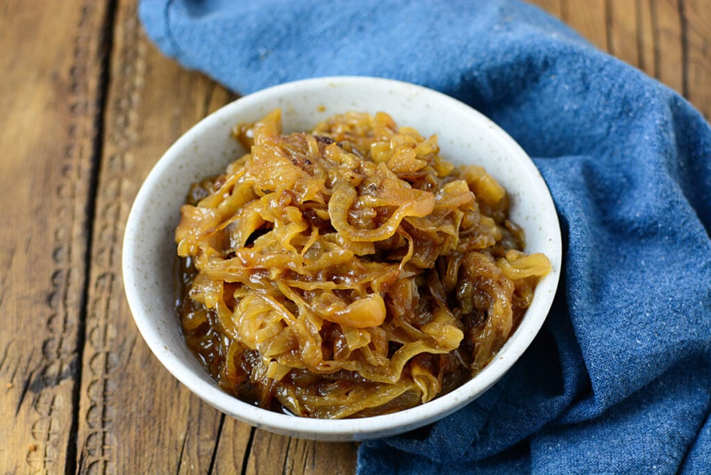 A small bowl of caramelized onions with a blue napkin beside it.