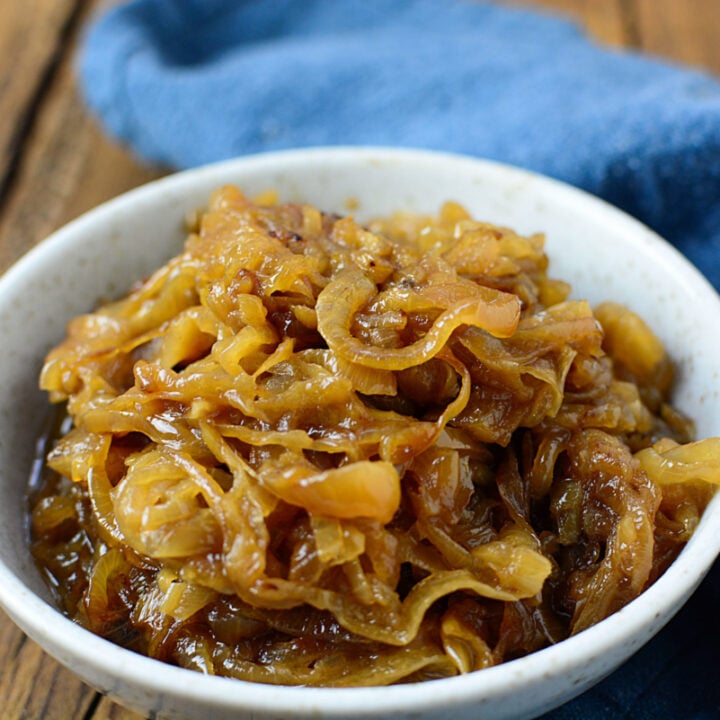 Caramelized onions in a white bowl with a blue napkin on the right.