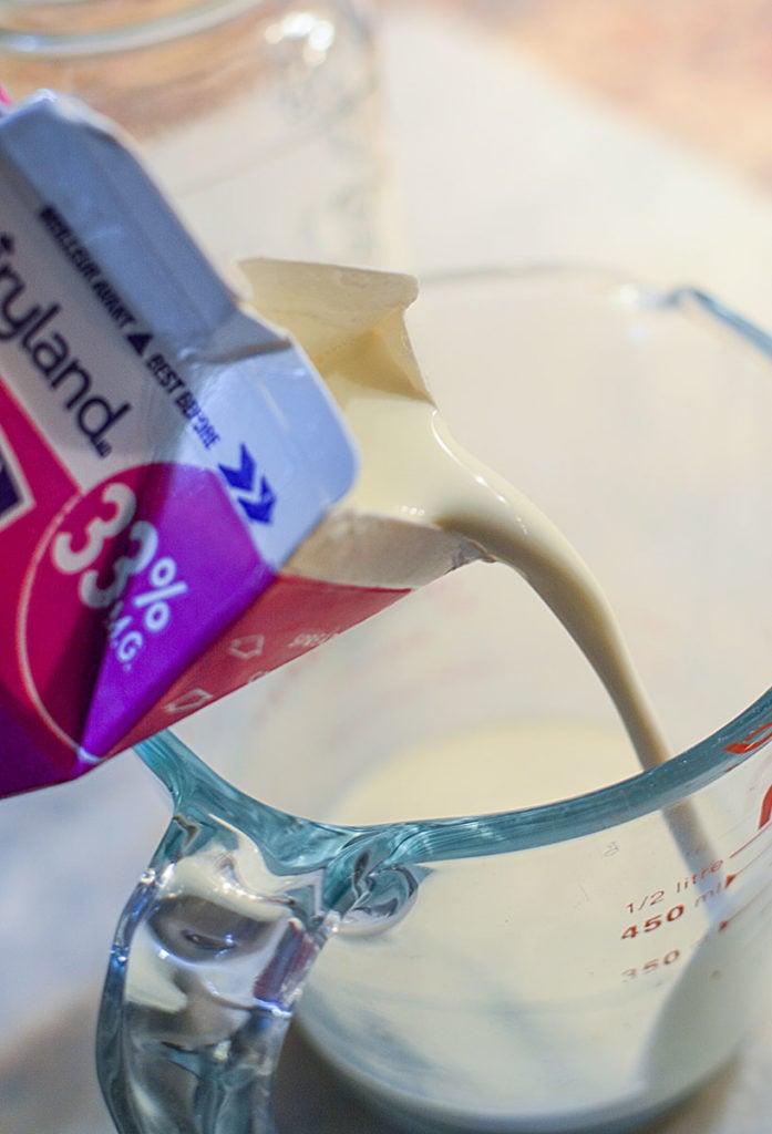 A close up image of milk from a tetra pack being poured into a glass measuring cup