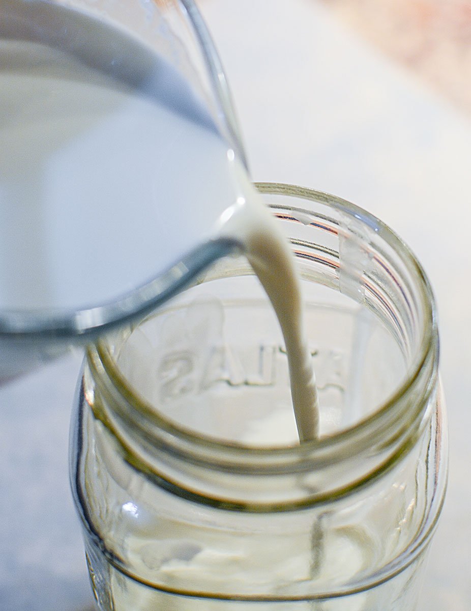 Pouring the cream and buttermilk mixture into a clean glass jar.