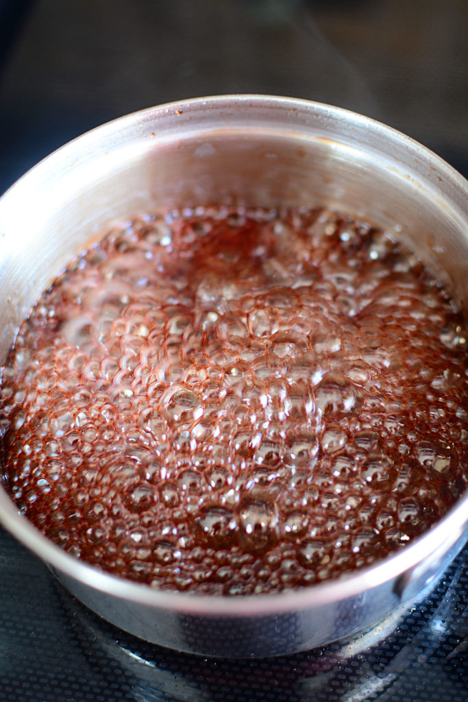 An image of a pot with boiling pomegranate juice on top of stove
