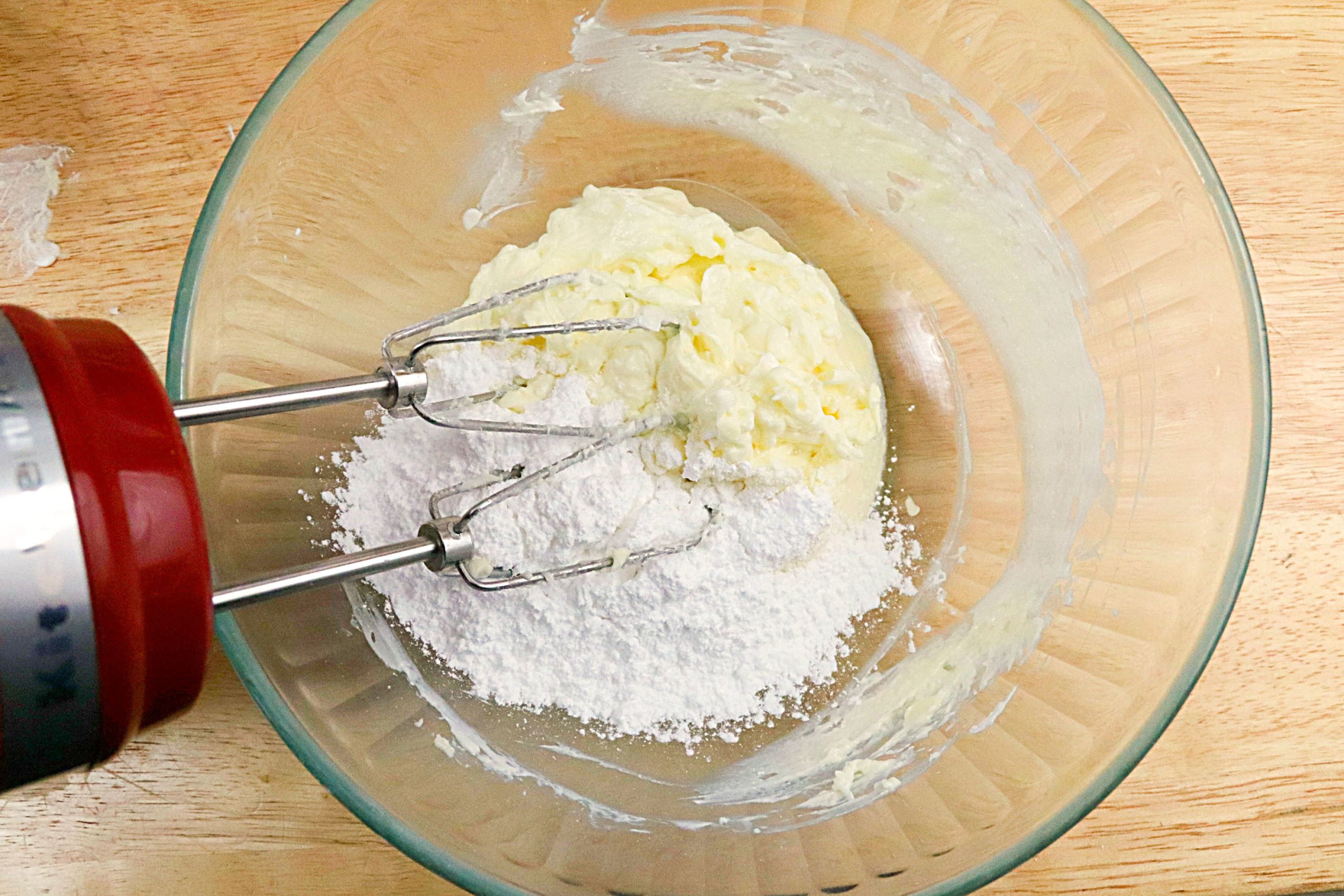Mixing the butter, cream cheese and icing sugar to a bowl to make the icing.