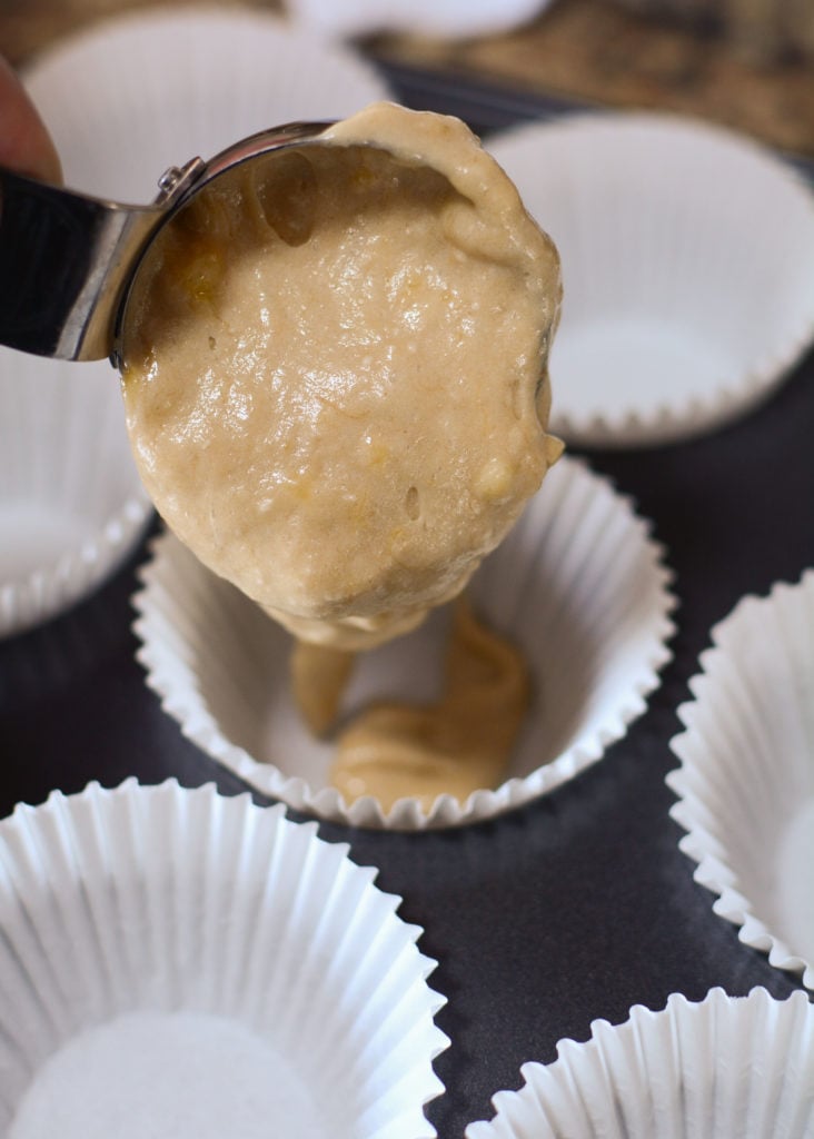 cake batter is poured into white cup cake liners