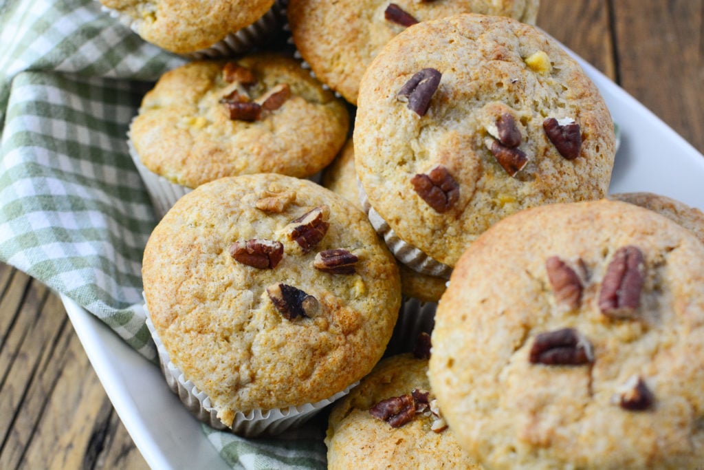 banana pecan muffins sitting on a white serving bowl with green napkin underneath