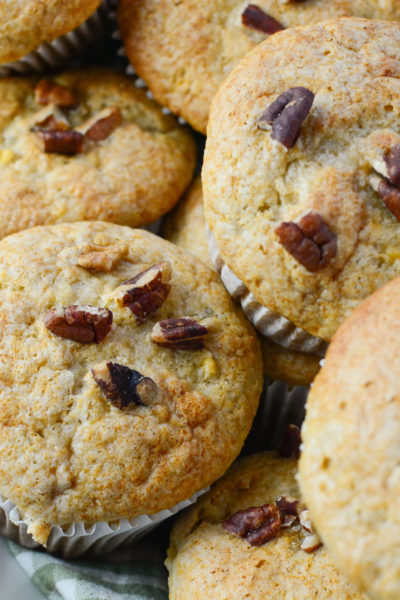 A basket of muffins with pecans on the top.