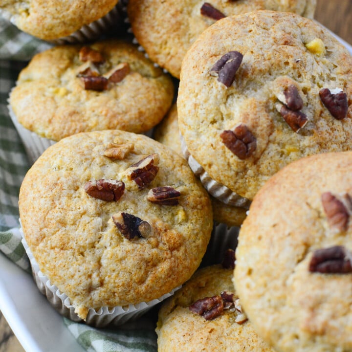 A basket of muffins with pecans on the top.