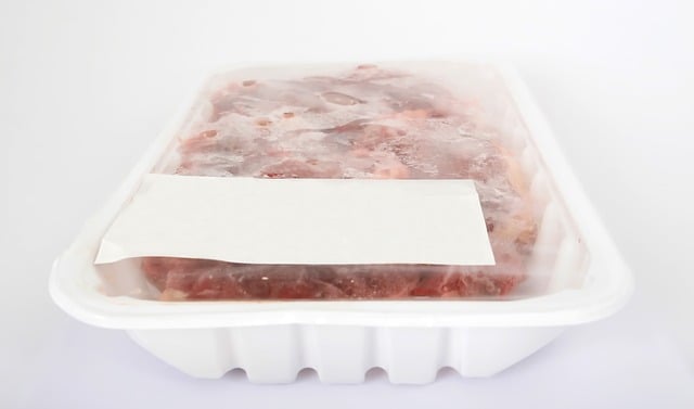 Slow cooked pulled chicken breast stored in a white plastic plate that is sealed with a white sticker on it for the date