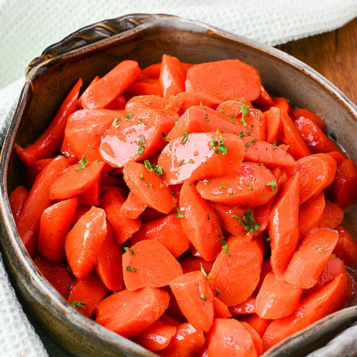 Cut carrots sitting in a green serving dish.