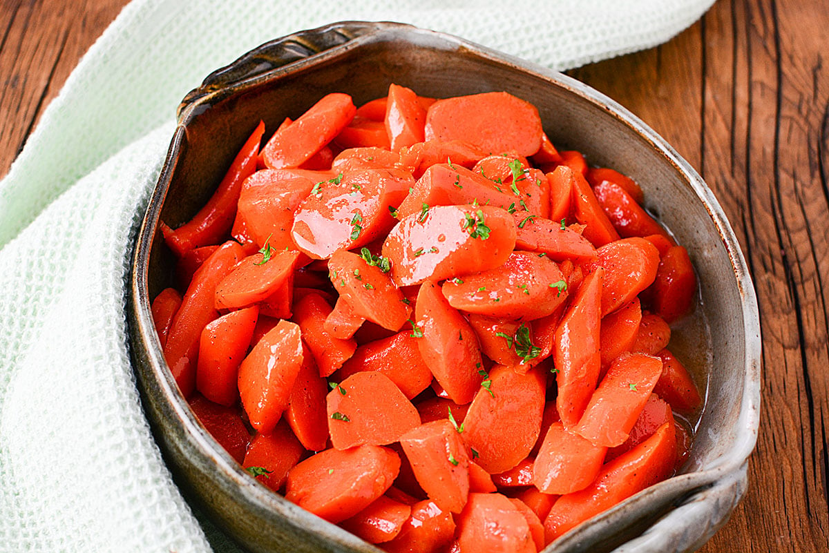 Cut carrots sitting in a green serving dish.