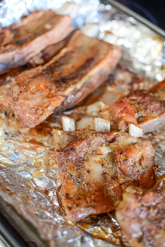 An image of 4 pieces of freshly cooked ribs on top of a foil. One piece showing three bones protruding from the meat