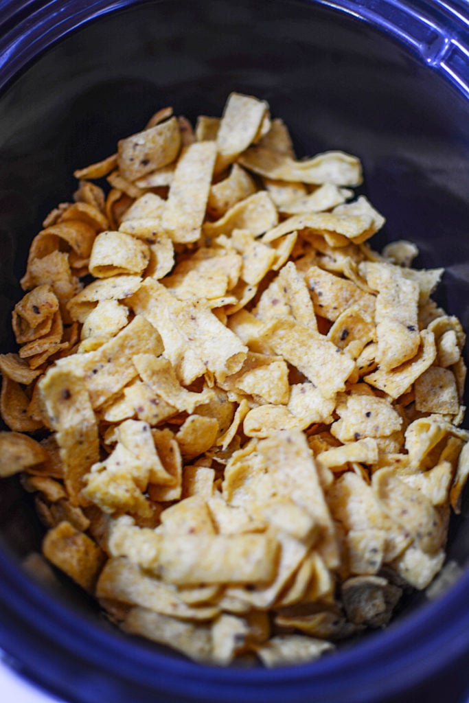 Regular plain corn chips sitting in a black slow cooker bowl ready to be seasoned