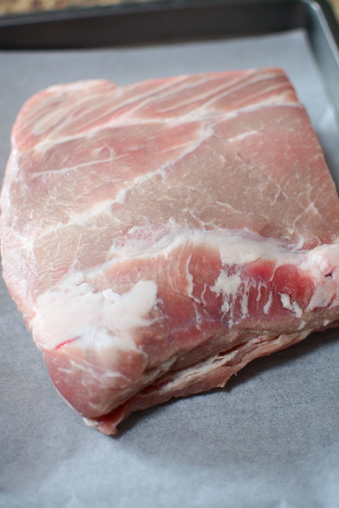 A piece of fresh pork laid out on a baking pan.