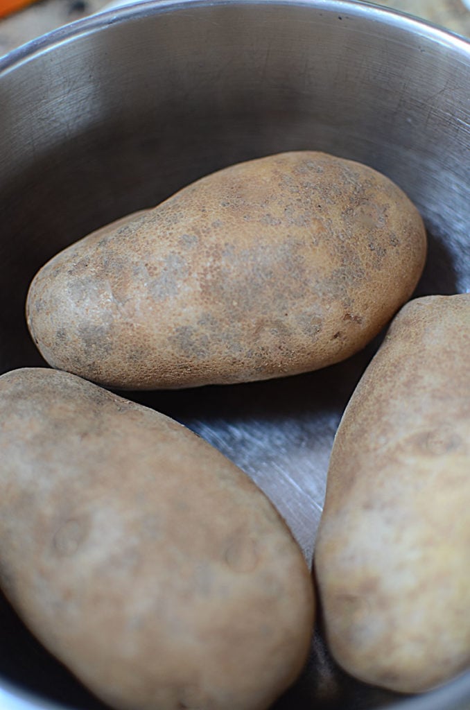 Three pieces of big, fresh potatoes in an empty pot