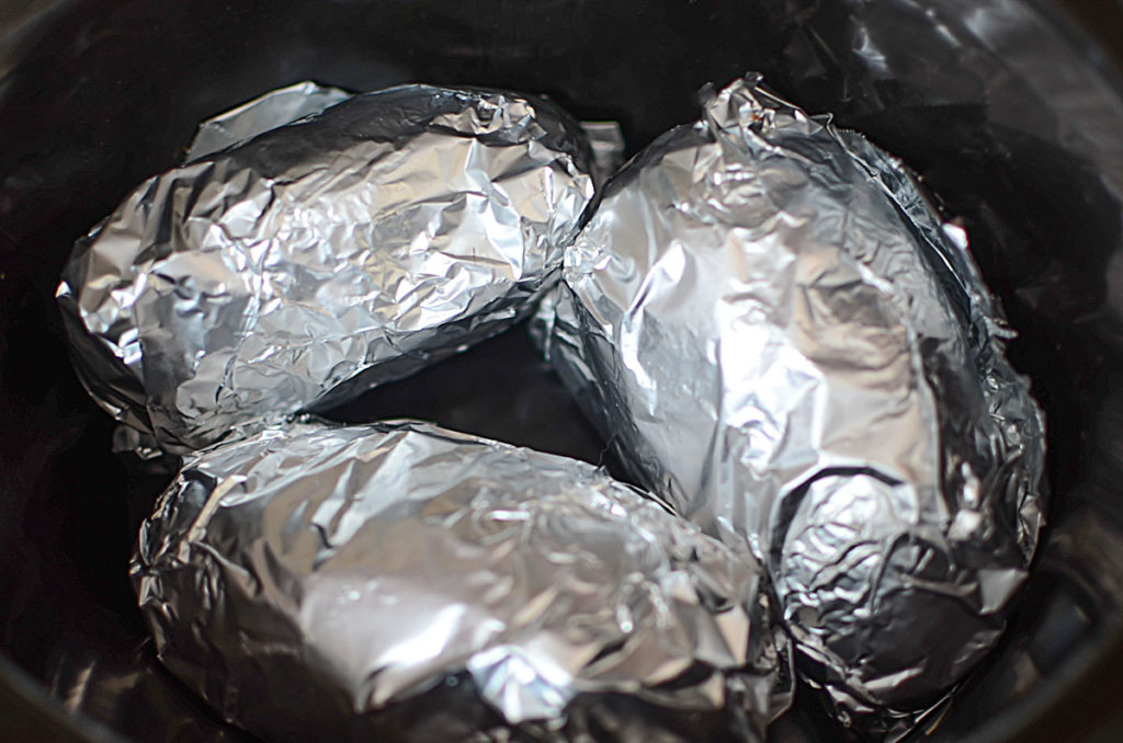 Three pieces of big potatoes wrapped in foil
