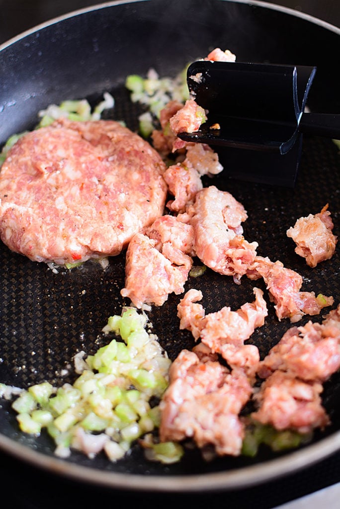 Sausage, diced celery and onions being fried in a frying pan