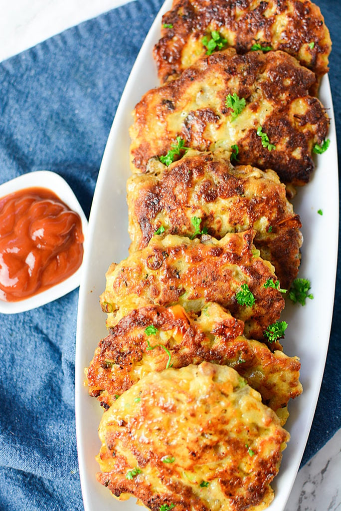 6 sausage and potato patties are so pretty lined up on a white plate with a side of ketchup to dip!