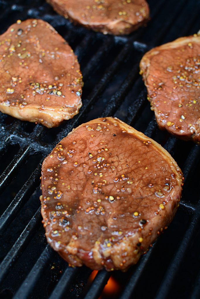 The marinated steaks on the grill.