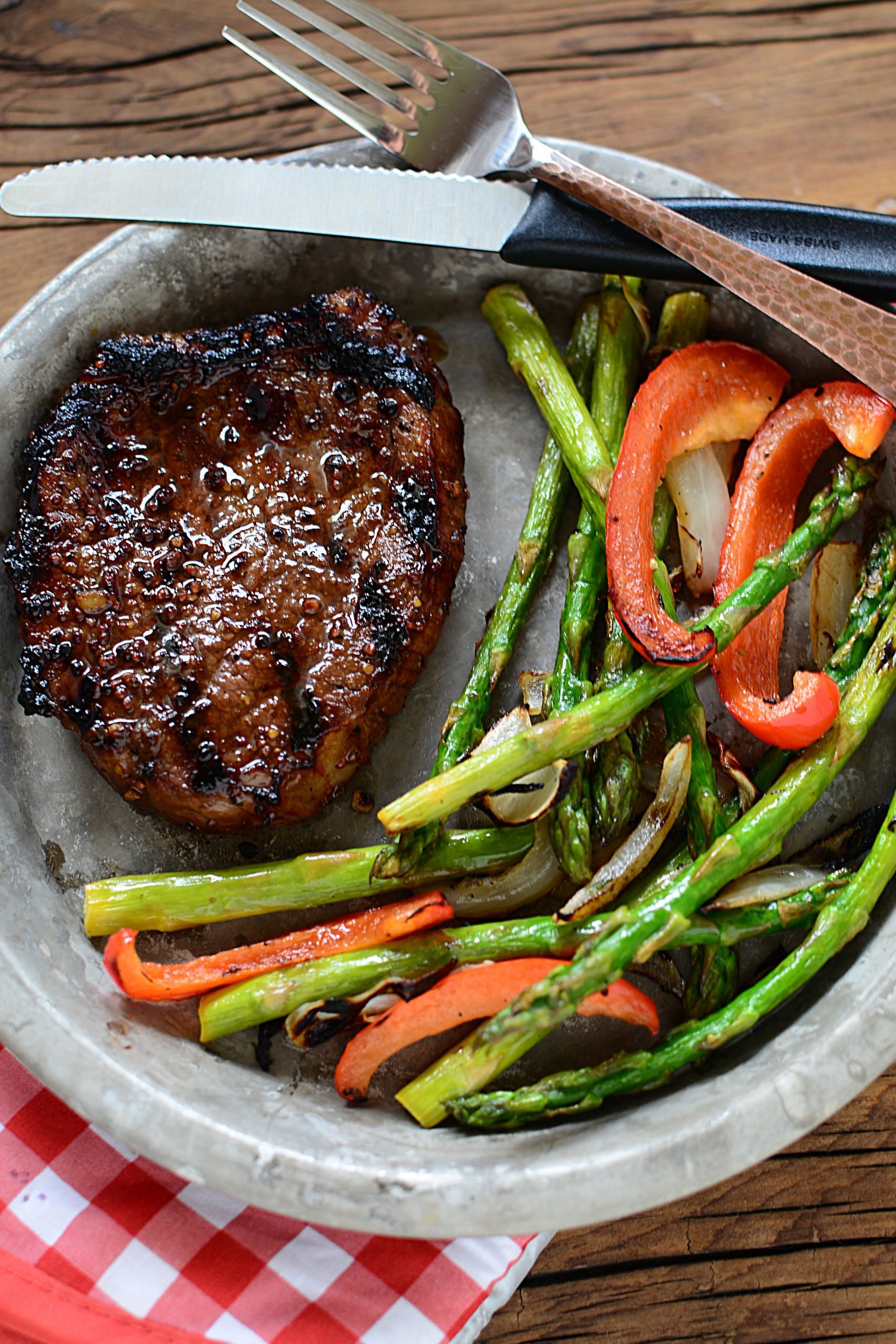 A grilled steak next to grilled vegetables.