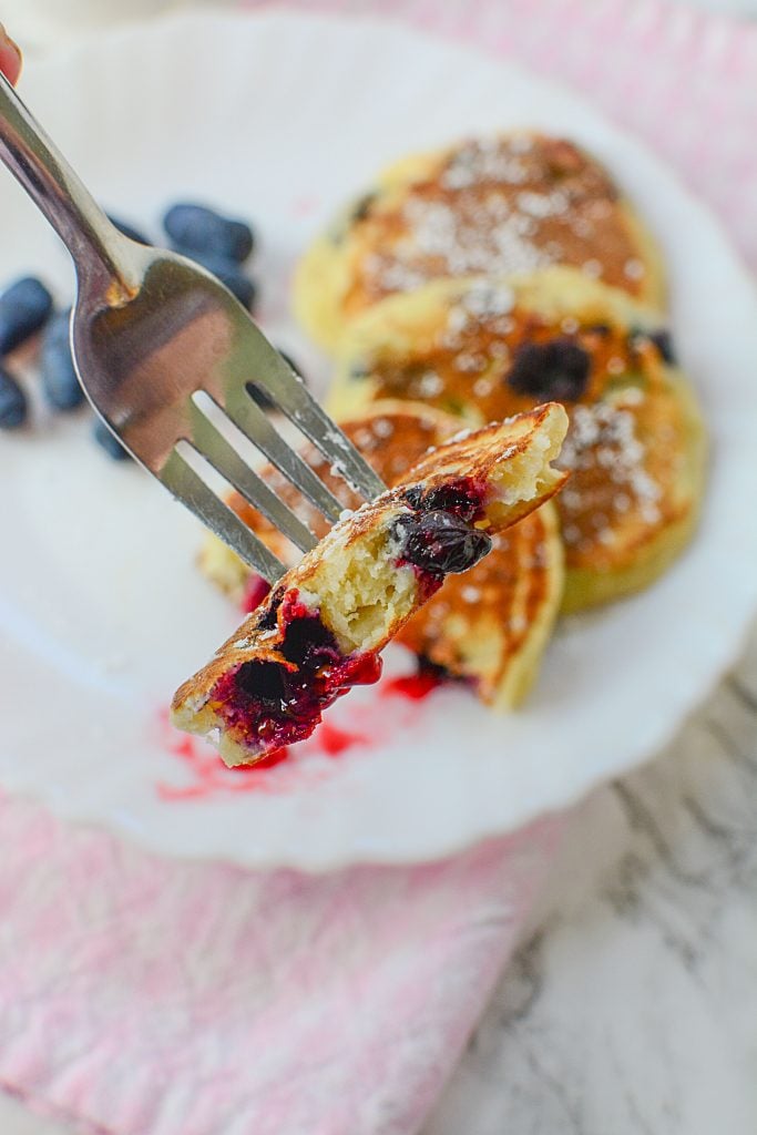 A fork with a cut portion of honey berry pancakes on the fork.