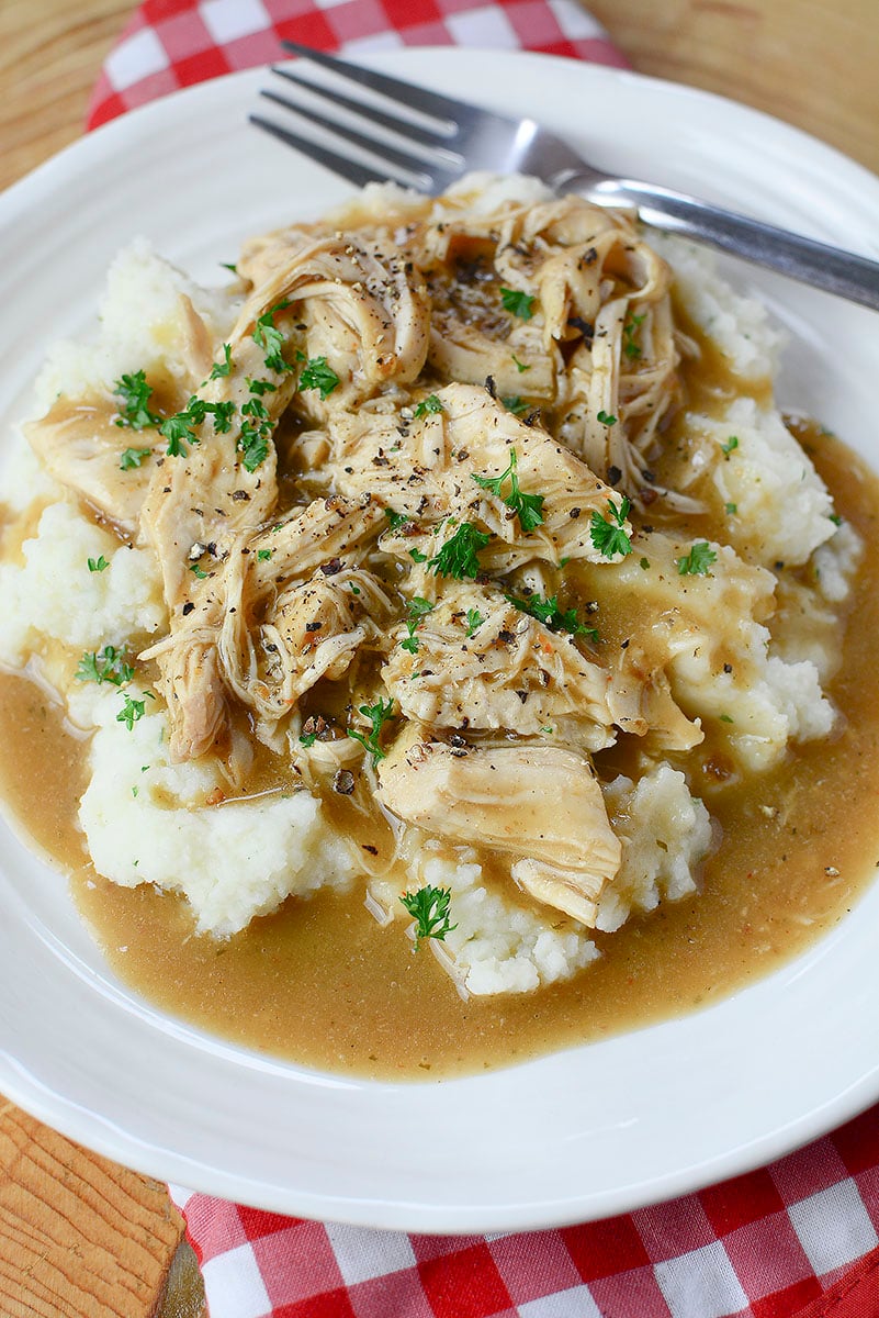 3 packet chicken with gravy on top of potatoes on a white plate.