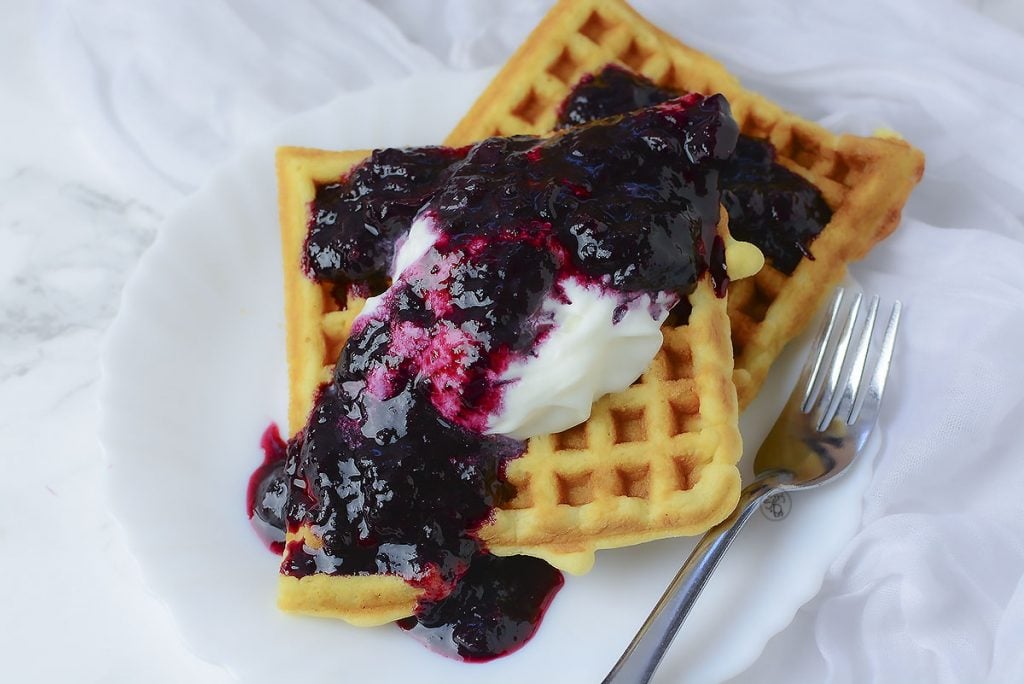 Delicious crispy waffle served with whipped cream and blueberry sauce