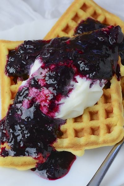 Delicious crispy waffle served with whipped cream and blueberry sauce