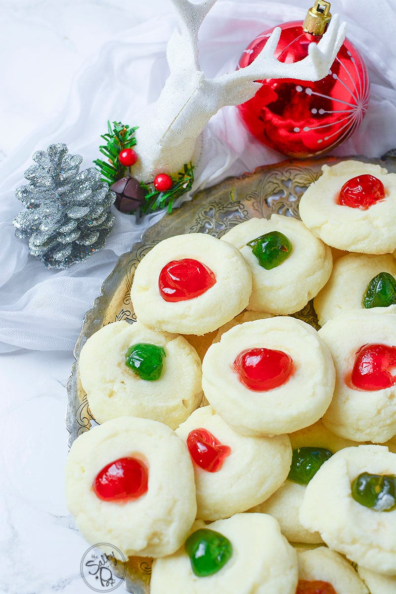 Christmas shortbread cookies on a metal tray with red, sliver and white christmas decorations on the top.