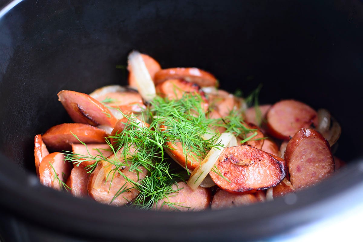 Garlic sausage and dill in the black slow cooker.