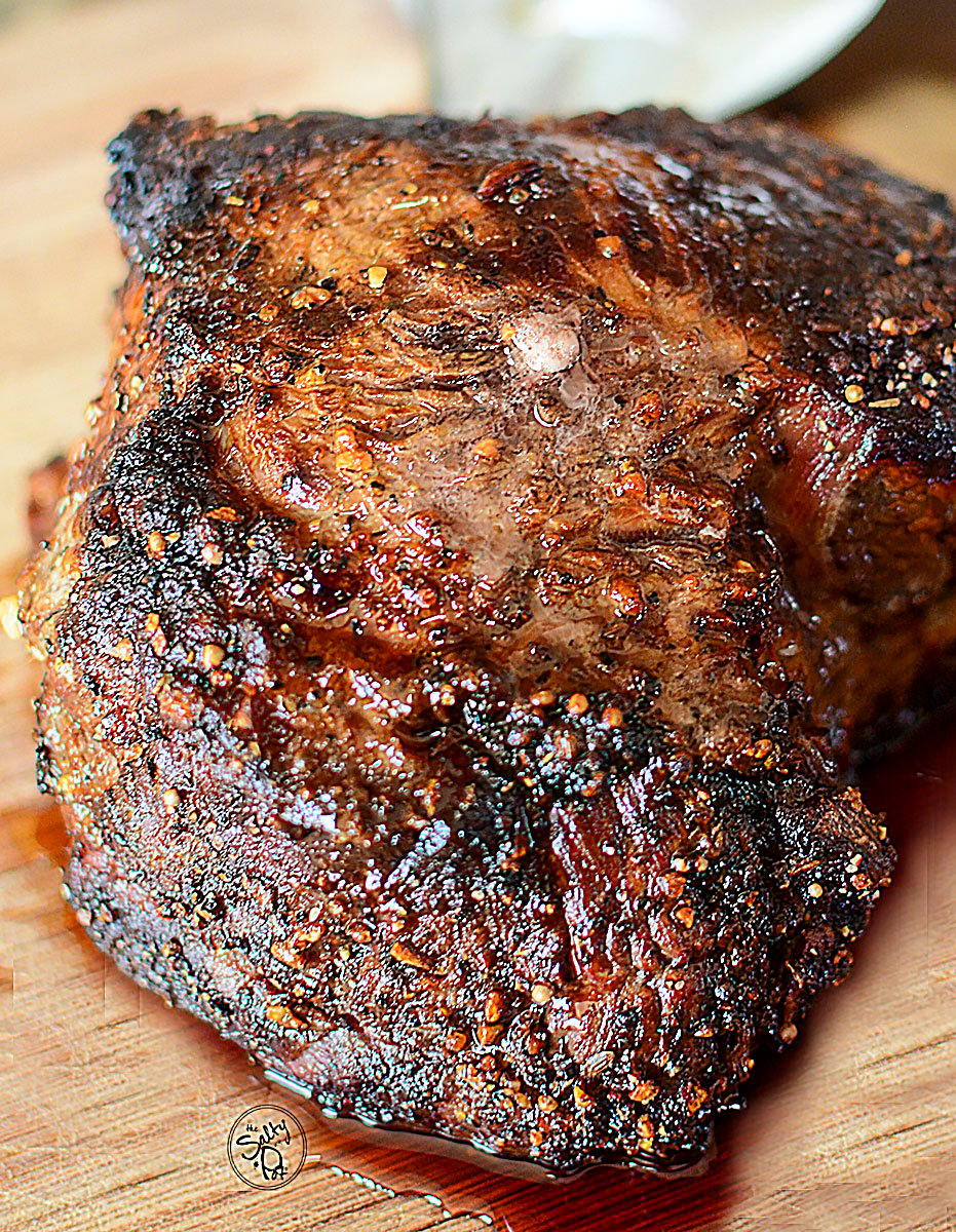 A large air fryer beef roast resting on a wooden cutting board after being cooked.
