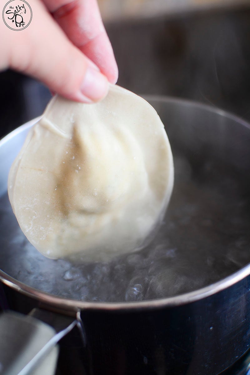 One dumpling about to be dropped into boiling water.