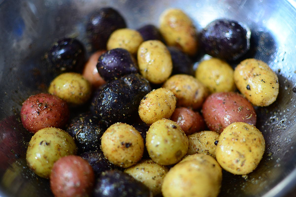 Seasoned creamer potatoes in a silver bowl ready to go into the ninja foodi air fryer.