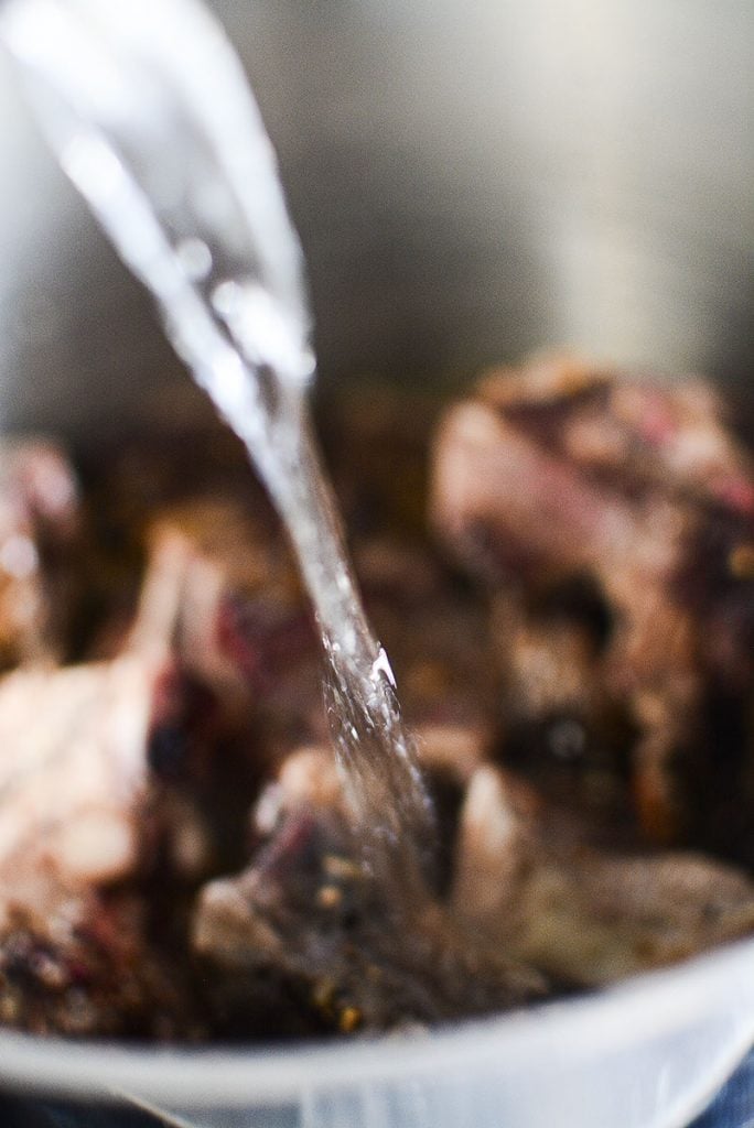 Pouring water into the roasted beef bones to make stock.