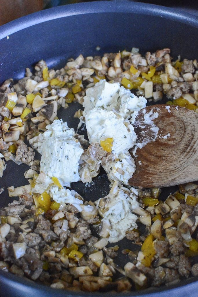 Adding the cheese to the sausage mixture in the fry pan. 