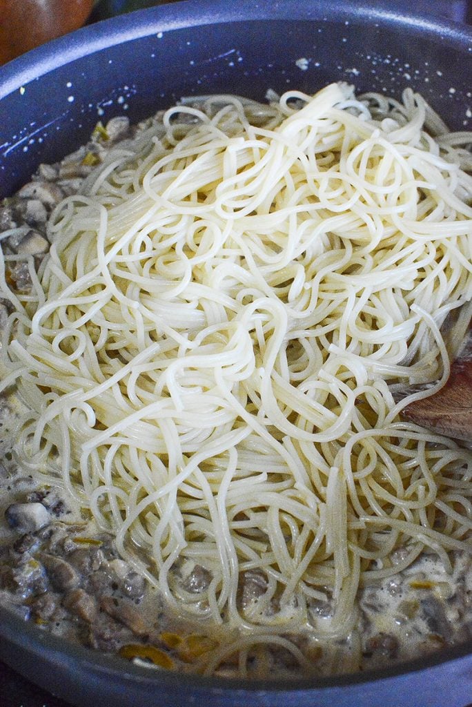 Adding the pasta to the sausage and creamy cheese sauce.