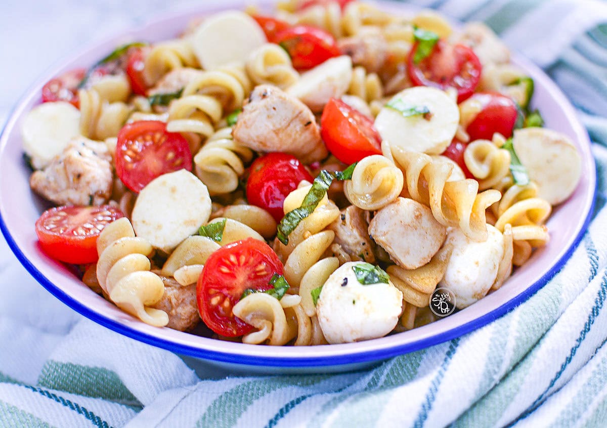 Caprese chicken salad in a blue lined bowl with a green napkin.