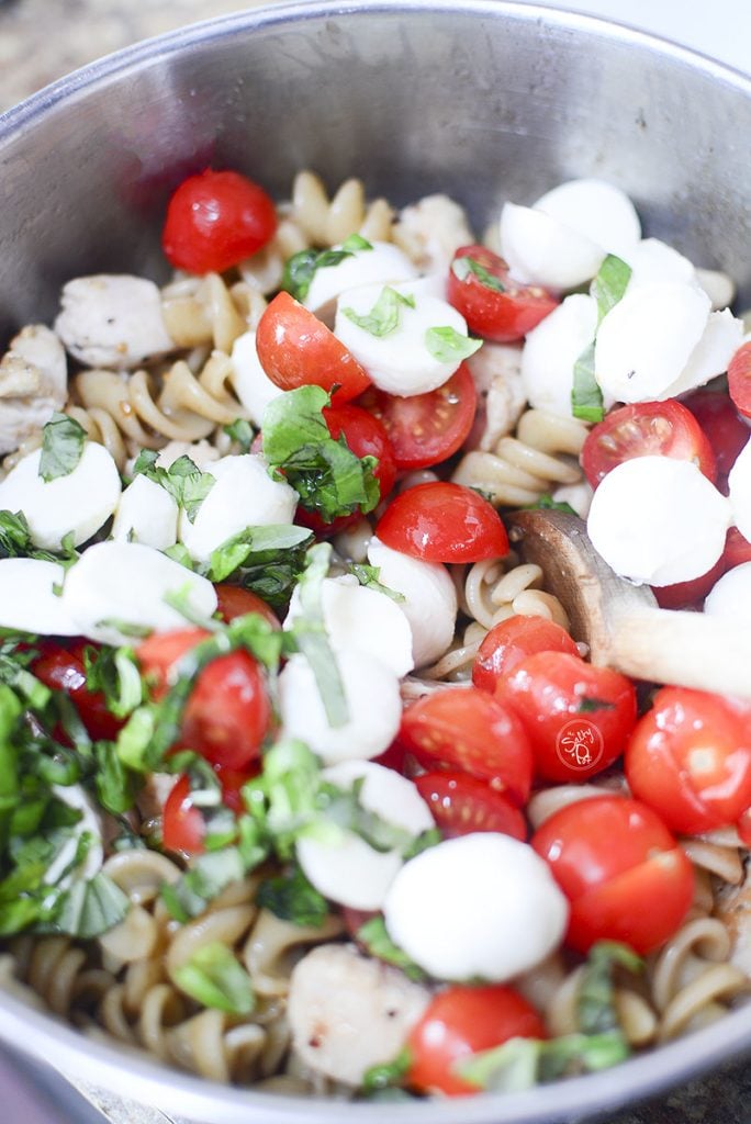 All of the ingredients that make up the pasta salad are in the bowl. It's not mixed yet, but when it is, it will be delicious!