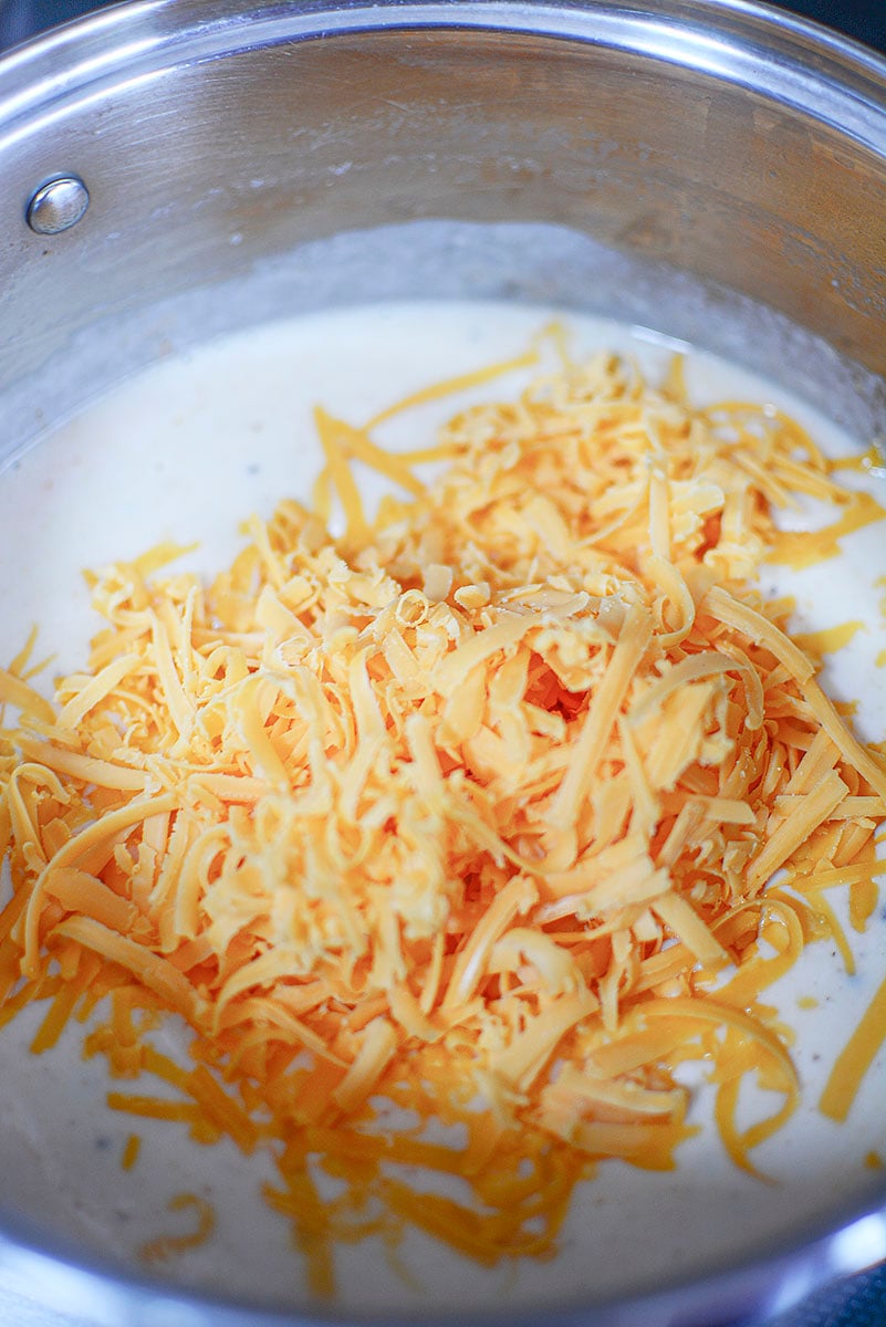 Shredded cheese going into the pot to be melted. 