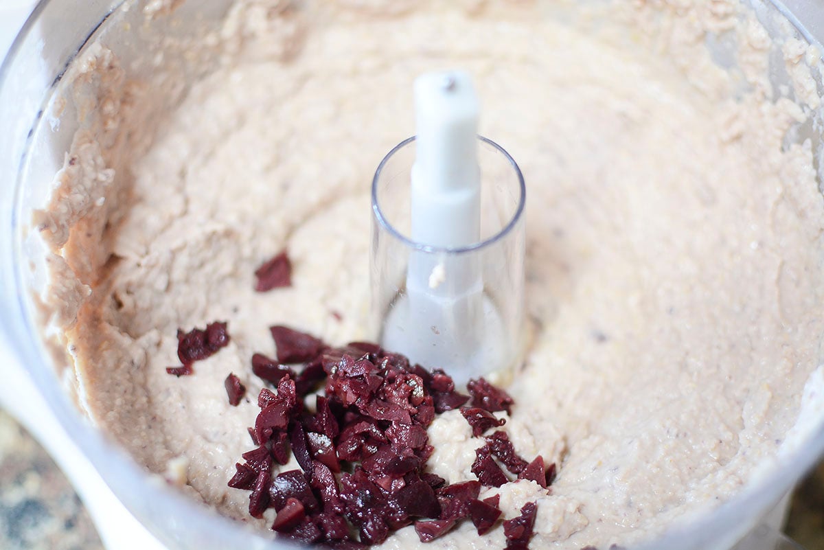 The black olives being added to the mixture to be blended.