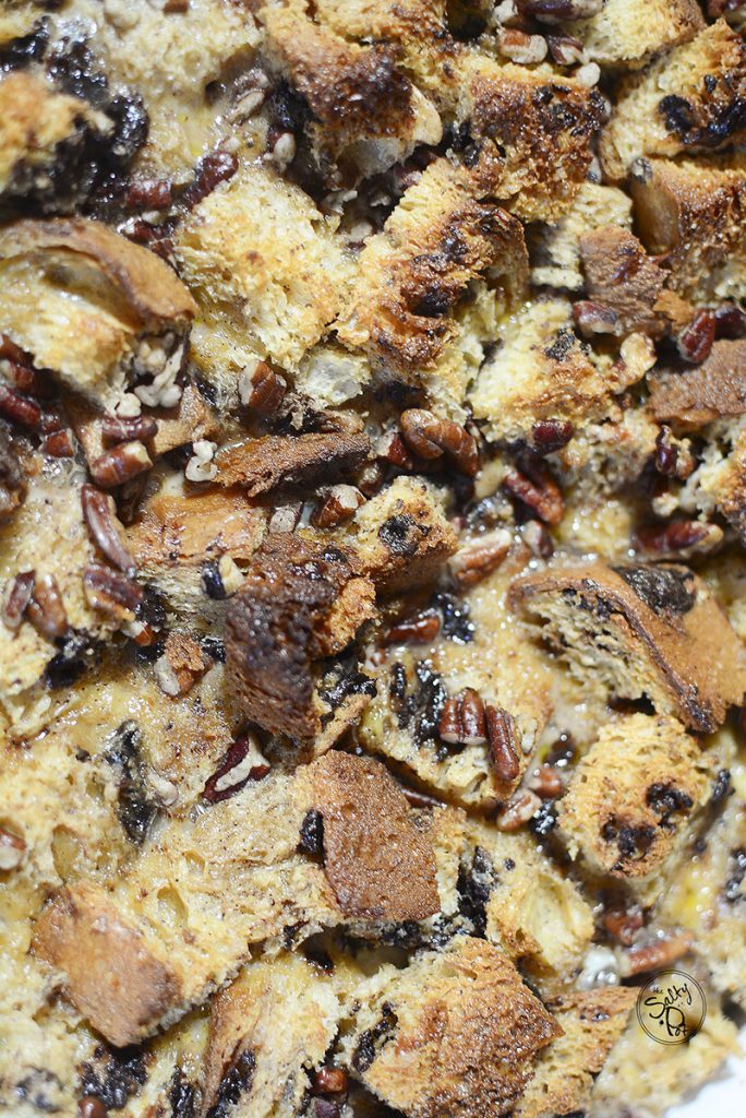A close up photo of the chocolate bread pudding with chocolate bits and pecans.