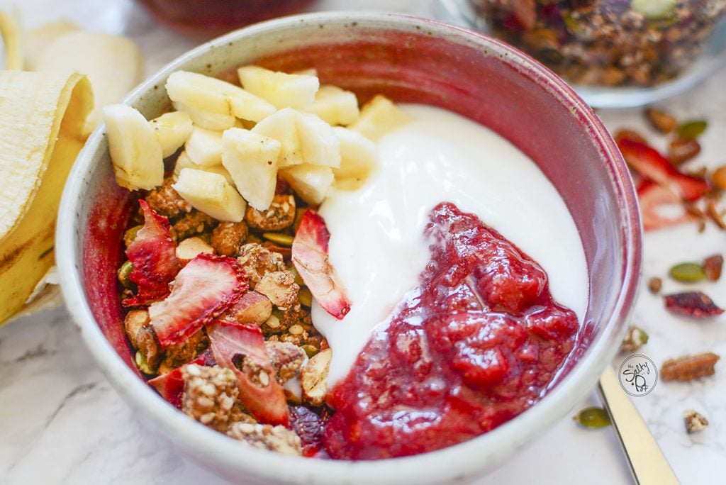 The granola bowl pictured has strawberry granola on the bottom, yogurt and strawberry compote on top, and then sliced banana in the corner of the bowl. Yum!