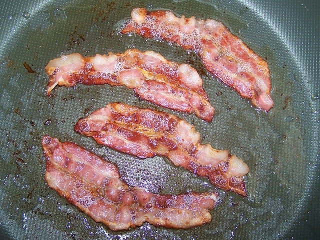 Four pieces of cooked bacon in a frying pan.