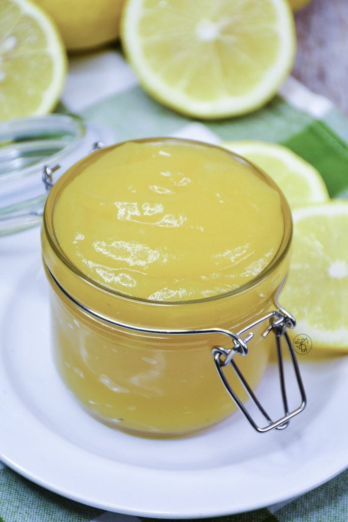 Lemon curd in a pretty jar surrounded by sliced lemons