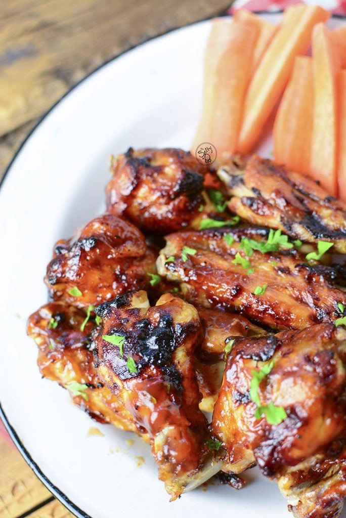 A photo of the right side of the dish with a close up on a few wings. The carrot sticks are at the top on the right side of the white plate.