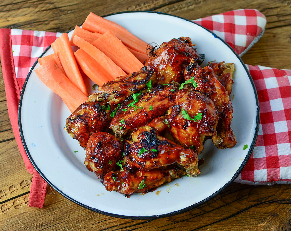 Ninja foodi bbq wings on a white plate with a red checked napkin underneath.