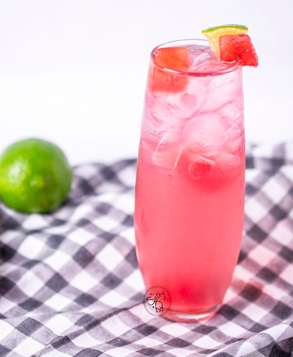 A full length photo of the drink and glass with a lime in the background to the left. 
