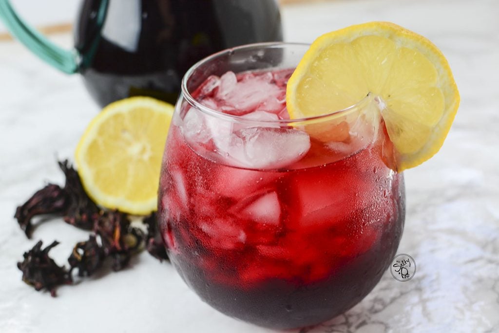 A 90 degree angle photo of the iced tea with lemon slices and dried hibiscus in the background.