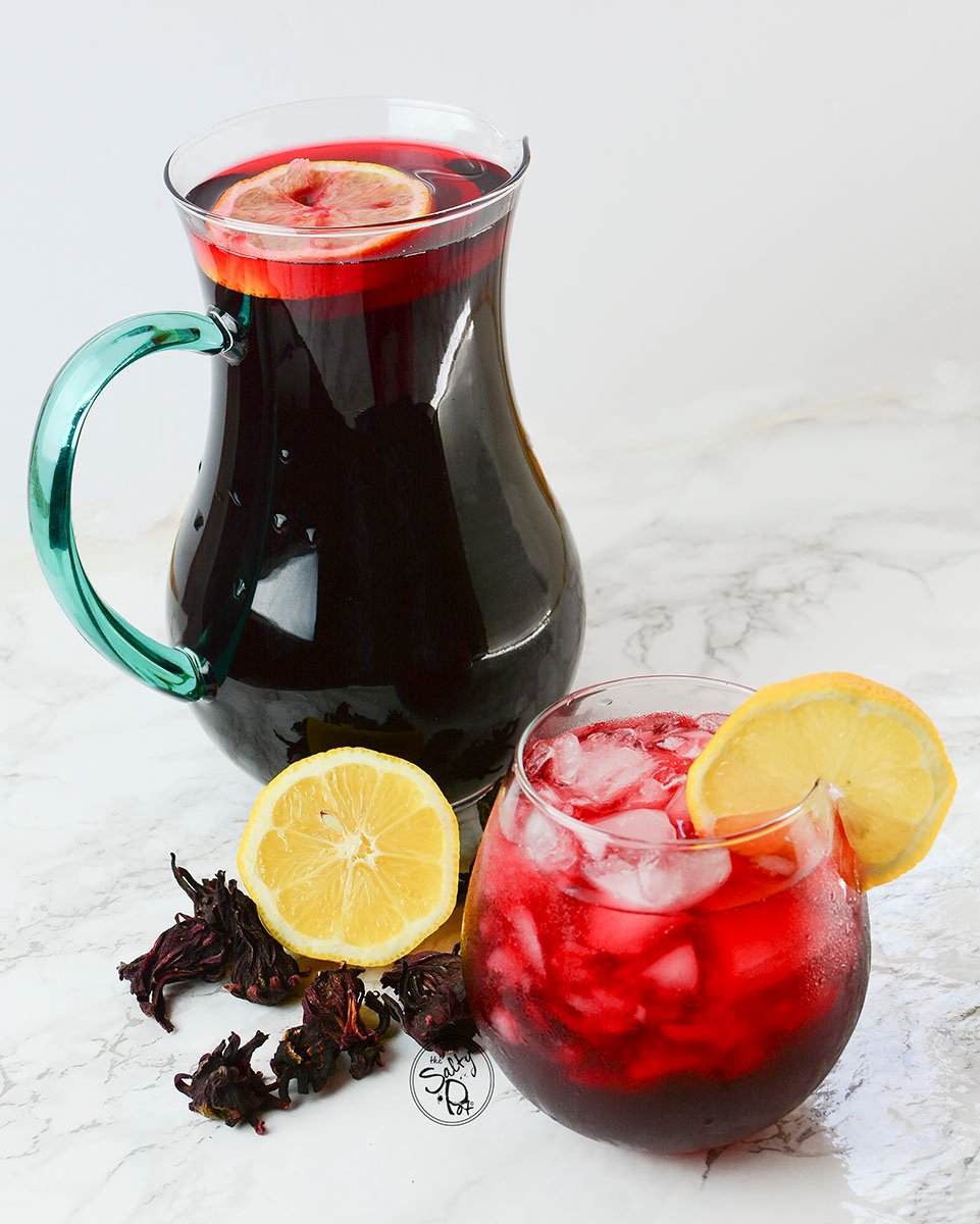 A pitcher and a glass with lemon slices and hibiscus tea.