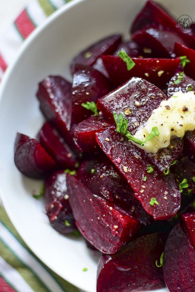 A photo showing half the bowl of beets with butter on top, closeup.